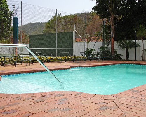 An outdoor swimming pool with chaise lounge chairs.