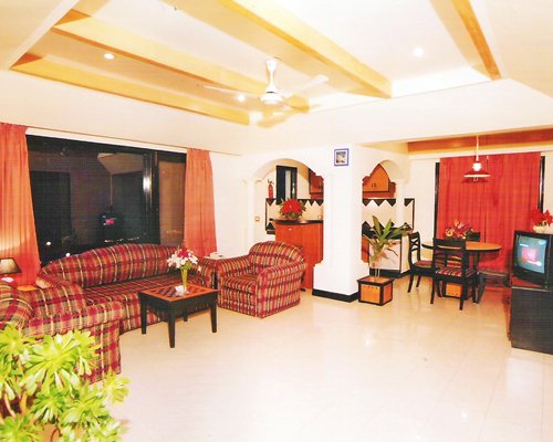 A well furnished living area with a television alongside kitchen with a dining area.