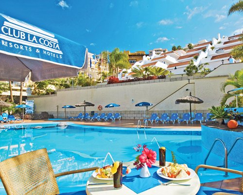 Outdoor swimming pool with chaise lounge chairs sunshades and outdoor dining.