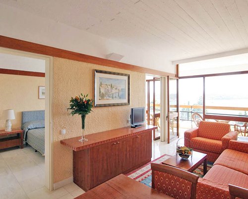 A well furnished living room with a television alongside a bedroom.
