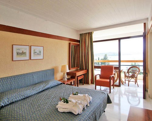 A well furnished bedroom with balcony and patio chairs.