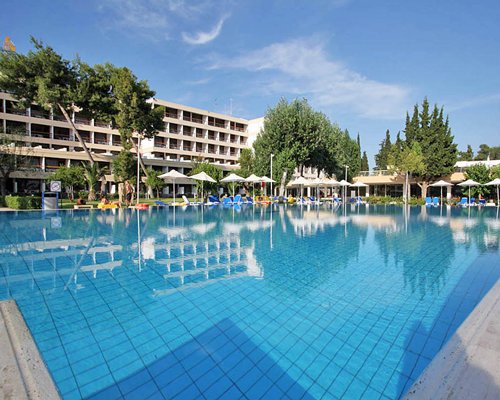 Large outdoor swimming pool with chaise lounge chairs and sunshades.