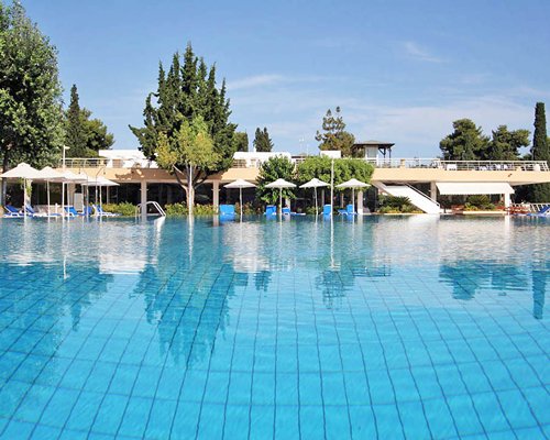 An outdoor swimming pool with chaise lounge chairs and umbrellas alongside the resort.