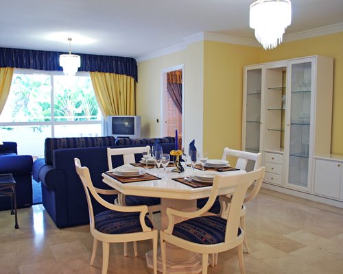A well furnished living room with television dining area and outside view.