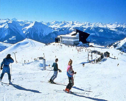 Group of people skiing alongside a resort unit and the rocks covered in snow.