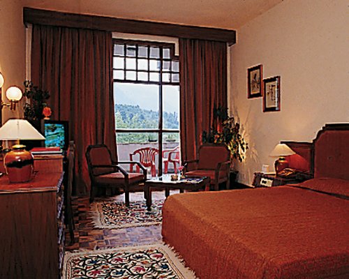 A well furnished bedroom with a double bed television and balcony.