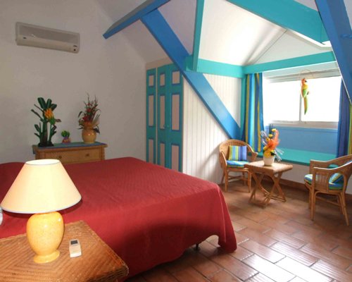 A well furnished bedroom with a lamp and chairs.