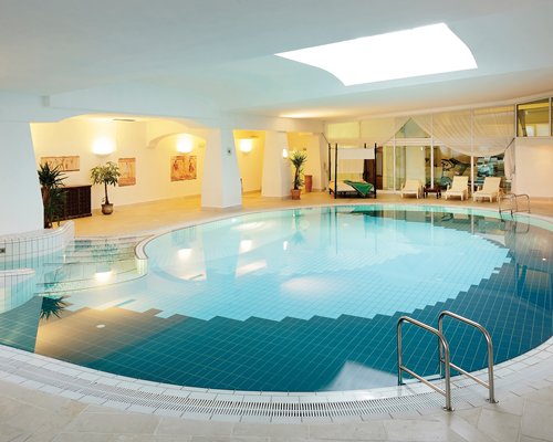 A large indoor swimming pool with chaise lounge chairs.