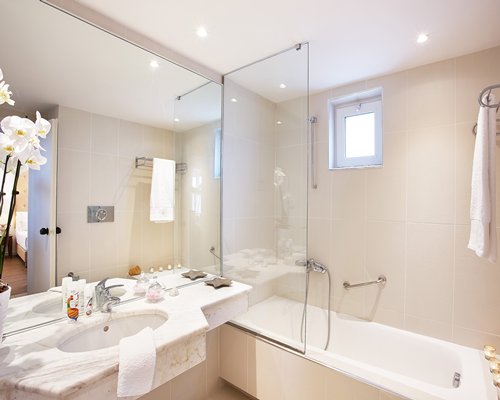 A bathroom with bathtub shower and single sink vanity.