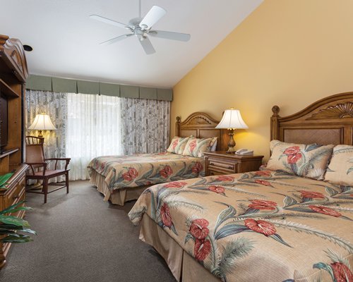 A well furnished bedroom with two beds and a television.