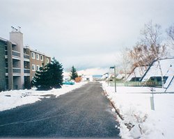 A street view of multi story resort units covered in snow.