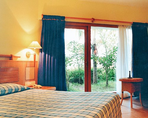 A well furnished bedroom with a lamp and an outside view.