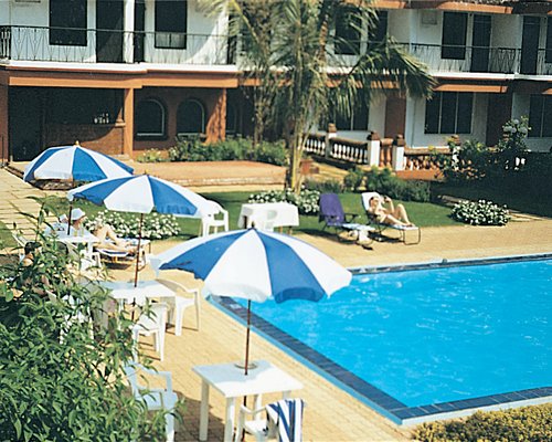 Outdoor swimming pool with chaise lounge chairs patio chairs and sunshades.