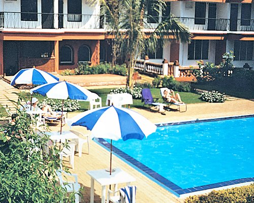 An outdoor swimming pool with chaise lounge chairs and patio furniture alongside resort units.