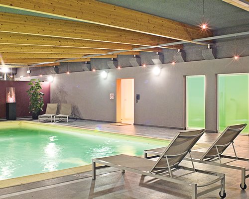 An indoor swimming pool with chaise lounge chairs.