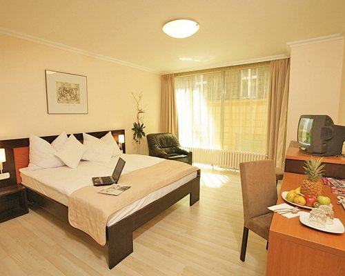 A well furnished bedroom with a television and laptop on the bed.
