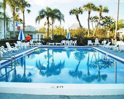 An outdoor swimming pool with chaise lounge chairs patio and sunshades.