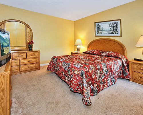 A well furnished bedroom with a dresser and television.