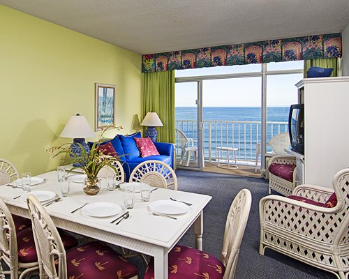 An open plan living and dining area with a television and a balcony.