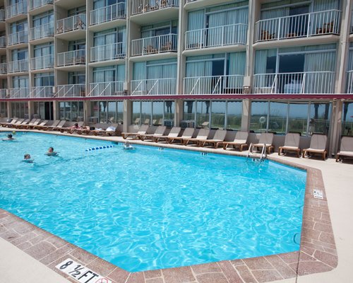 An outdoor swimming pool with chaise lounge chairs.