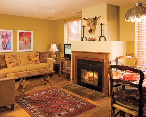 A well furnished living area with a television fire at the fireplace alongside a dining area.