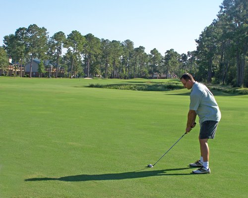A man playing in a well maintained golf course.
