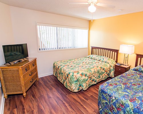 A well furnished bedroom with two twin beds and a television.