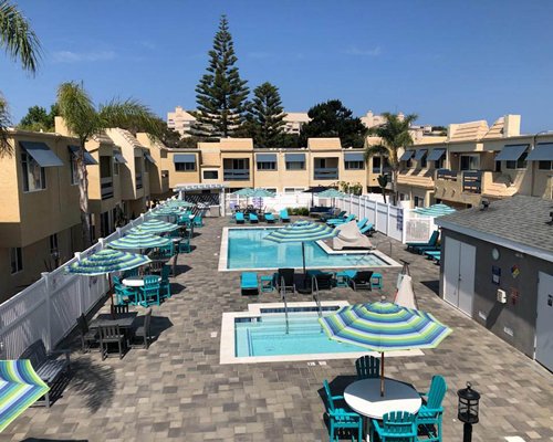 An outdoor swimming pool with sunshades and chaise lounge chairs alongside the resort.