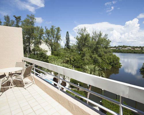 Balcony with patio chairs alongside the water and wooded area.