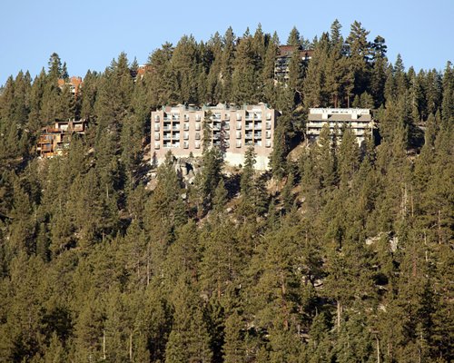 An exterior view of multi story resort units surrounded by wooded area.