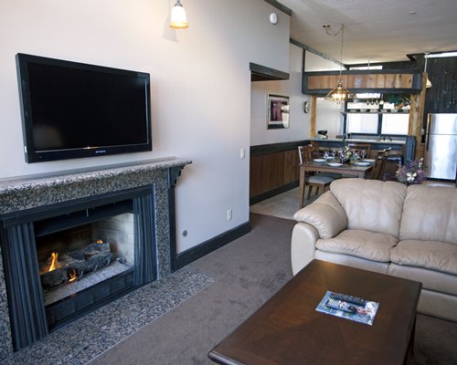 An open plan living and dining area with a television and fire in the fireplace.