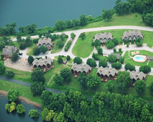 An aerial view of the resort properties alongside the lake surrounded by wooded area.