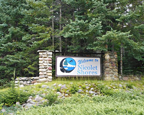 Signboard of the Nicolet Shores resort alongside the trees.