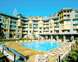 An outdoor swimming pool with chaise lounge chairs alongside multi story units.