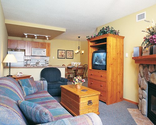 A well furnished living room with a television and fireplace alongside kitchen.