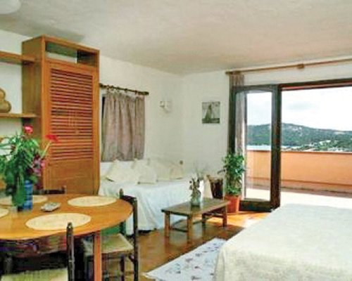 An open plan bedroom and dining area with a balcony.