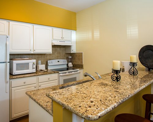 A well equipped kitchen with a microwave oven and a breakfast bar.