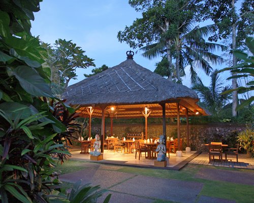 A well furnished outdoor dining area surrounded by trees.