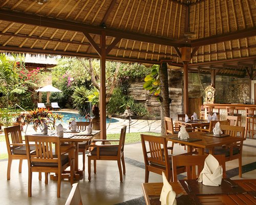 Outdoor restaurant alongside a swimming pool with chaise lounge chairs sunshade and landscaping.