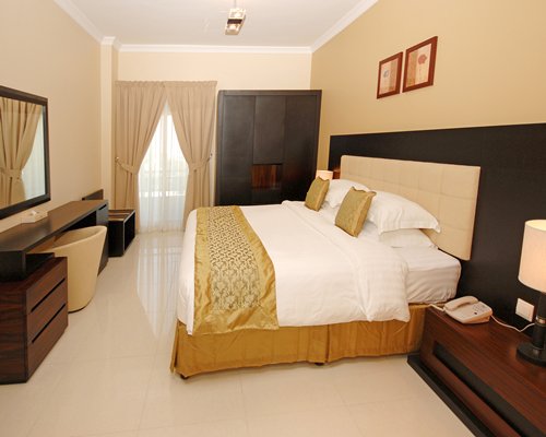 A well furnished bedroom with king bed and balcony.