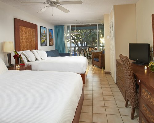 A well furnished bedroom with two beds television balcony and sea view.
