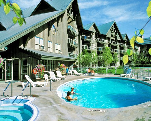 An outdoor swimming pool and hot tub with chaise lounge chairs alongside the resort units.