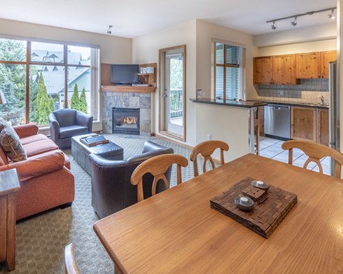 A well furnished living room with a television fireplace dining area and open plan kitchen.