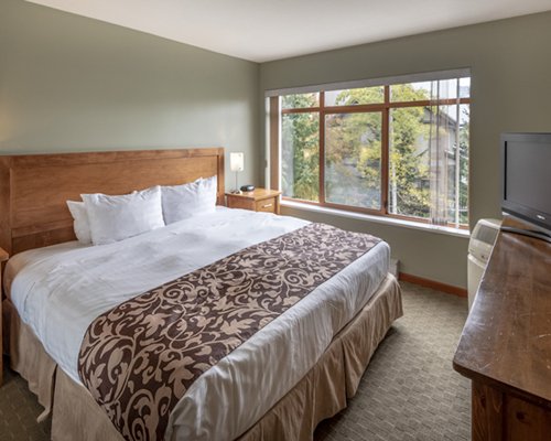 A well furnished bedroom with a queen bed and television.