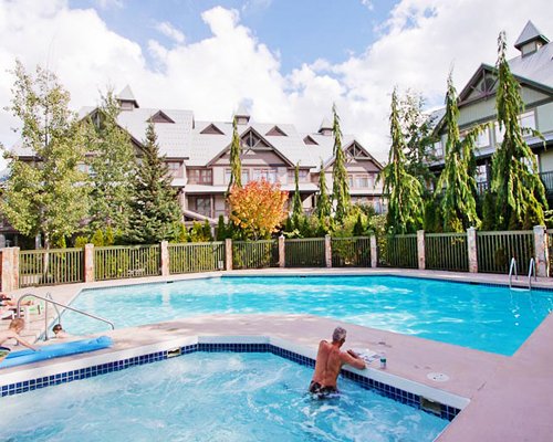 Two outdoor swimming pools with trees alongside resort units.