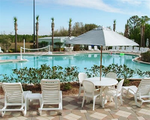 An outdoor swimming pool with pool volleyball chaise lounge chairs and sunshades.