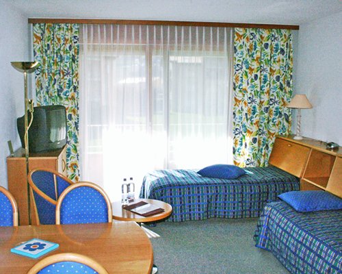A well furnished bedroom with two twin beds television dining area and balcony.