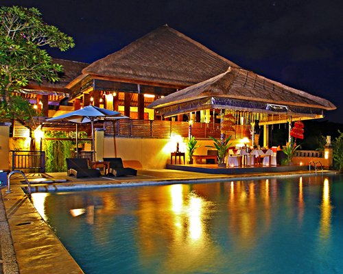 An outdoor swimming pool alongside resort units at dusk.