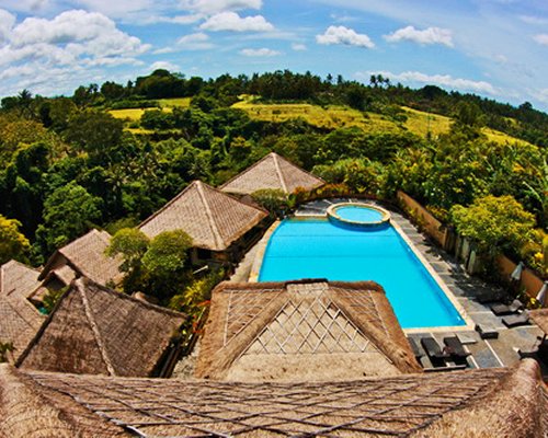 An outdoor swimming pool and hot tub alongside the resort surrounded by trees.