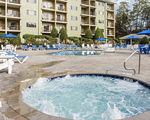 An outdoor swimming pool with chaise lounge chairs alongside the multi story resort unit.